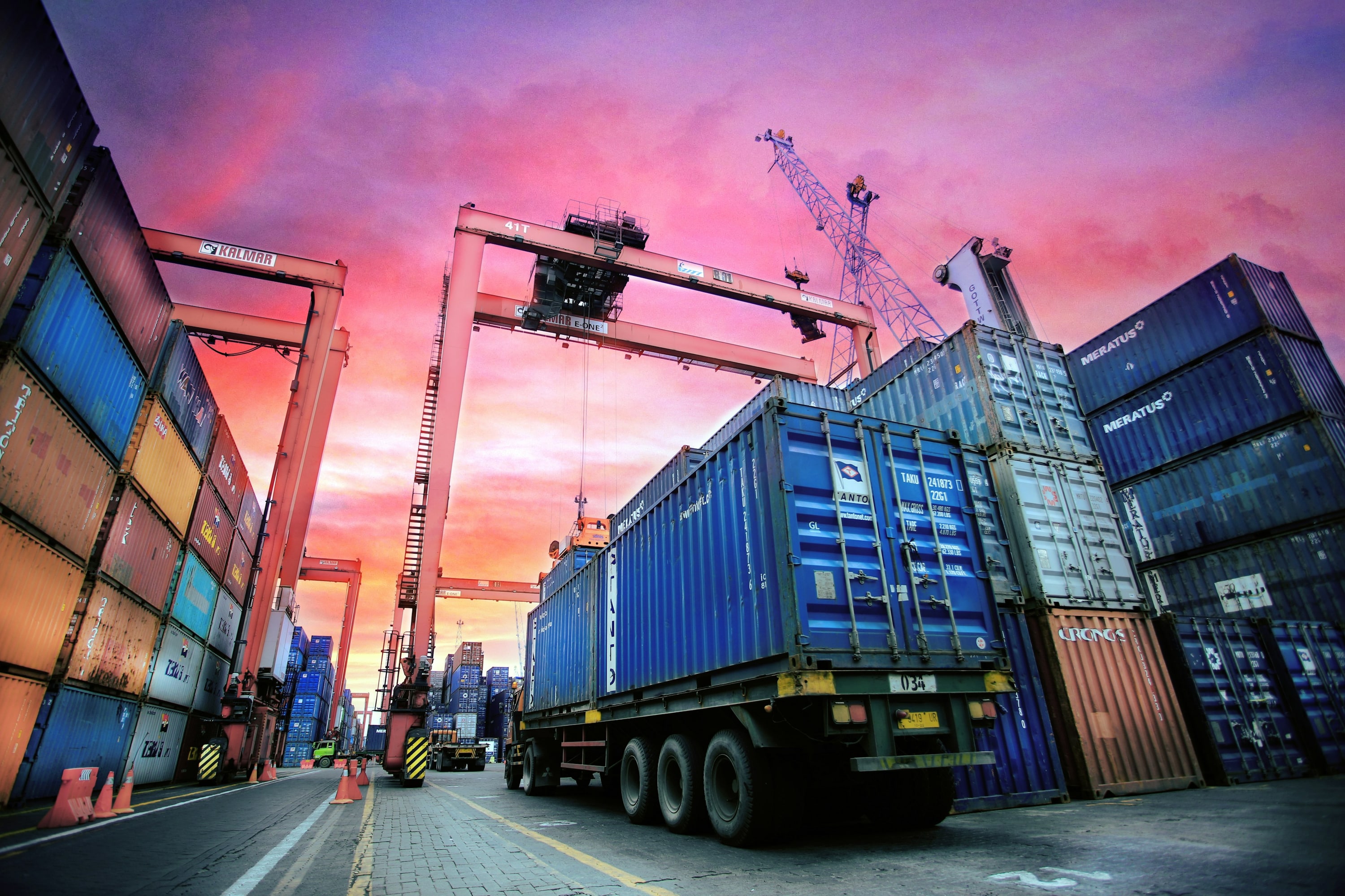 Tractocamión con contenedor en una terminal portuaria al atardecer